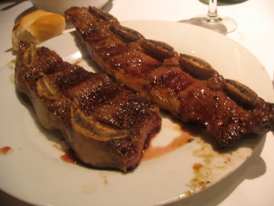 Dos tiras de costilla vacuna asadas, con marcas de parrilla, servidas en un plato
