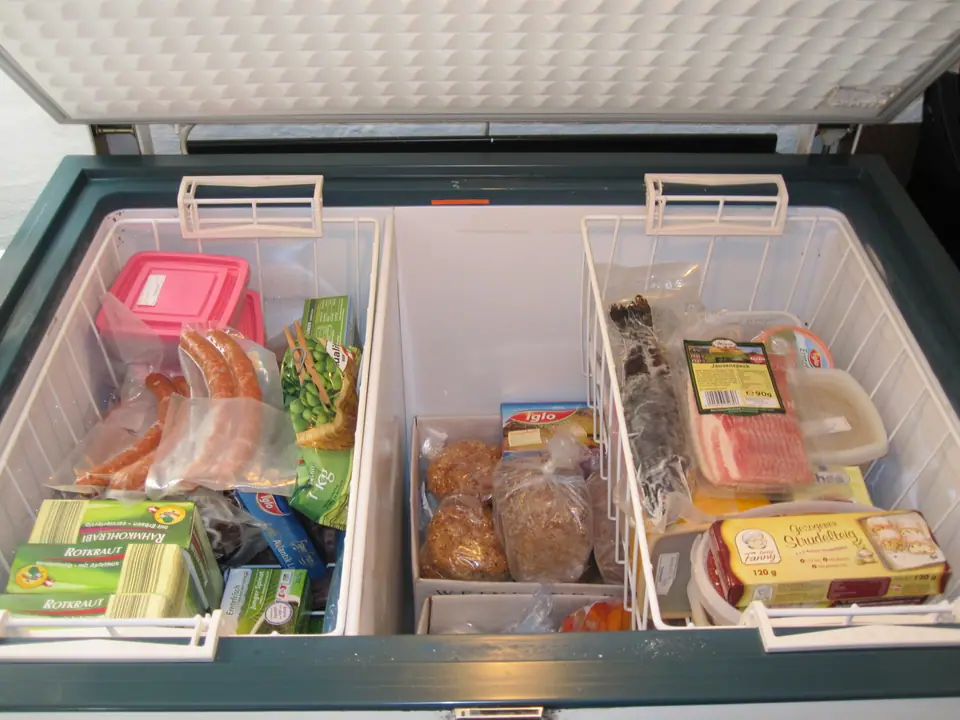 Freezer horizontal abierto con alimentos congelados en canastos
