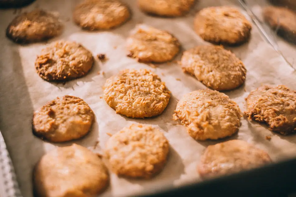 Galletas caseras redondas y doradas sobre papel de horno en una bandeja