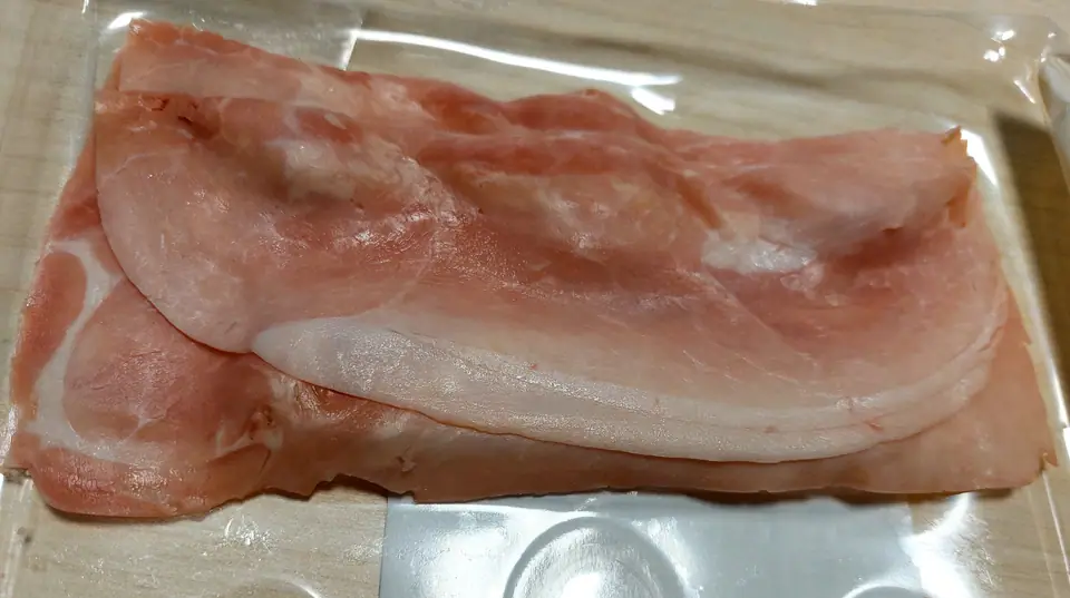 Fetas de jamón cocido apiladas en una bandeja plástica