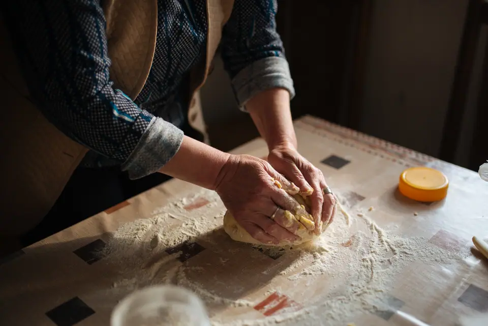 Manos amasando masa de pan sobre una mesa enharinada