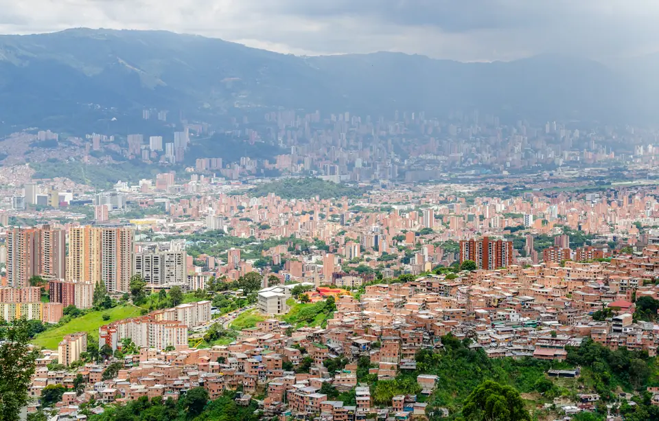 Vista panorámica de Medellín en el valle, con edificios y barrios en las laderas y montañas al fondo
