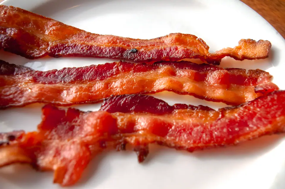 Fetas de panceta dorada y crocante sobre un plato blanco