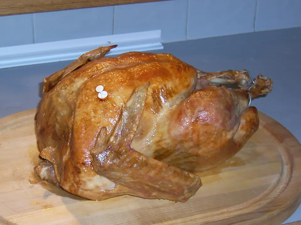Pavo entero asado y dorado sobre una tabla de madera