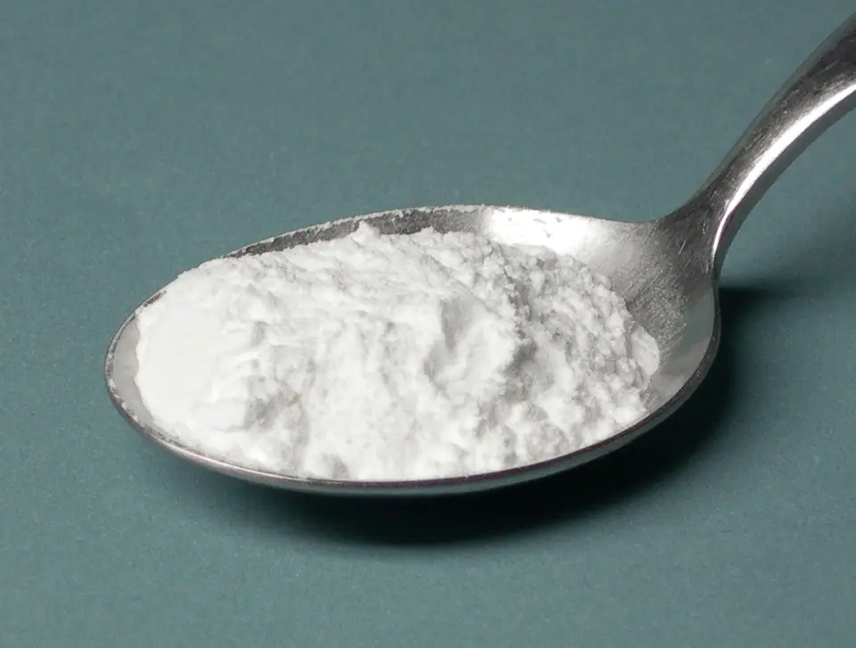 Cuchara de metal colmada de polvo de hornear blanco