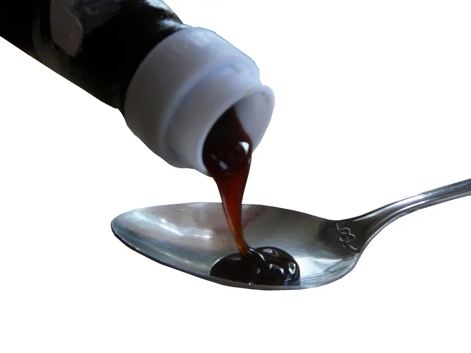 Salsa espesa y oscura que cae de una botella a una cuchara