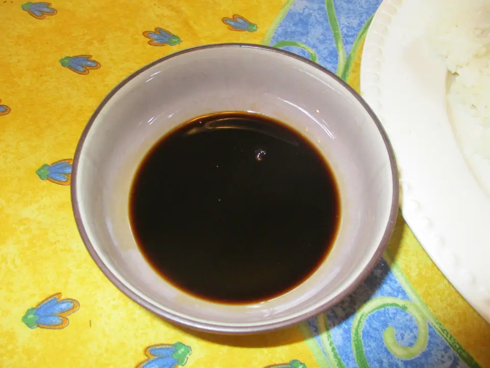 Cuenco pequeño con salsa de soja oscura sobre un mantel de colores