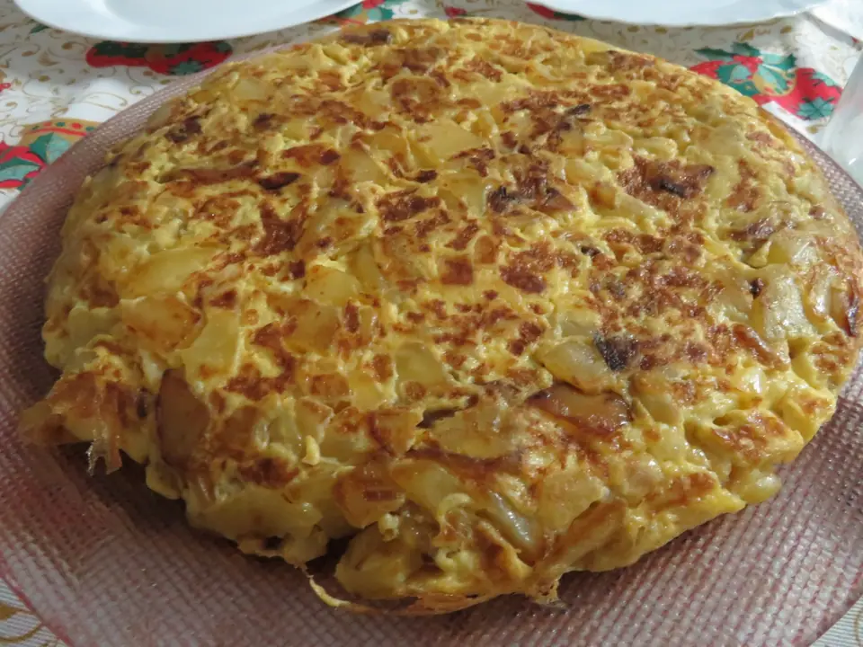 Tortilla de papas entera y dorada sobre un plato